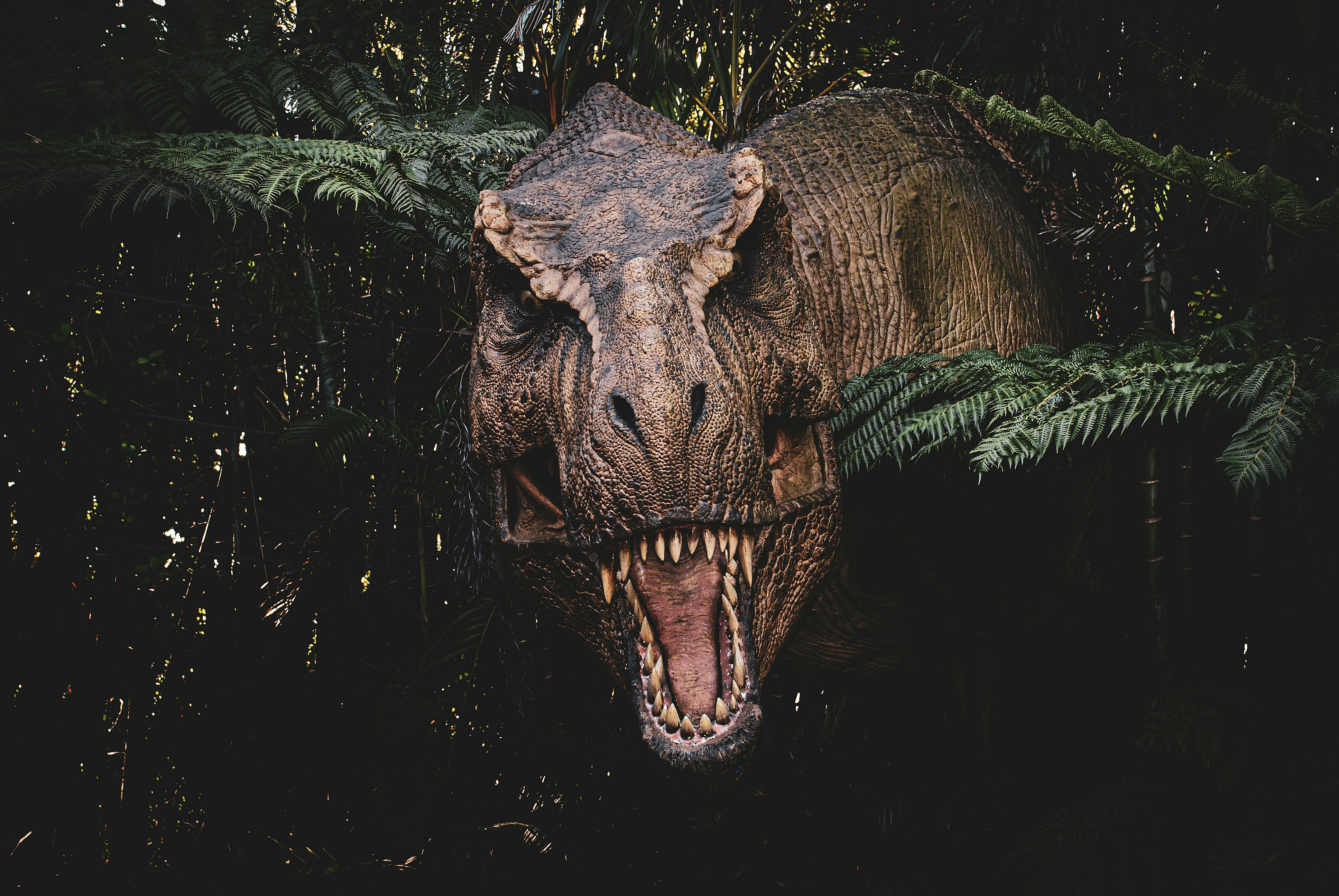 a large dinosaur with its mouth open in a forest