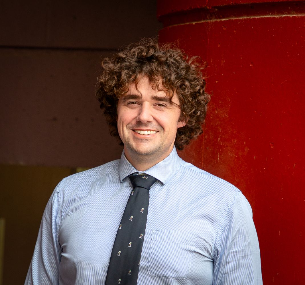 Tim Bartlett-Taylor in front of a plain red background