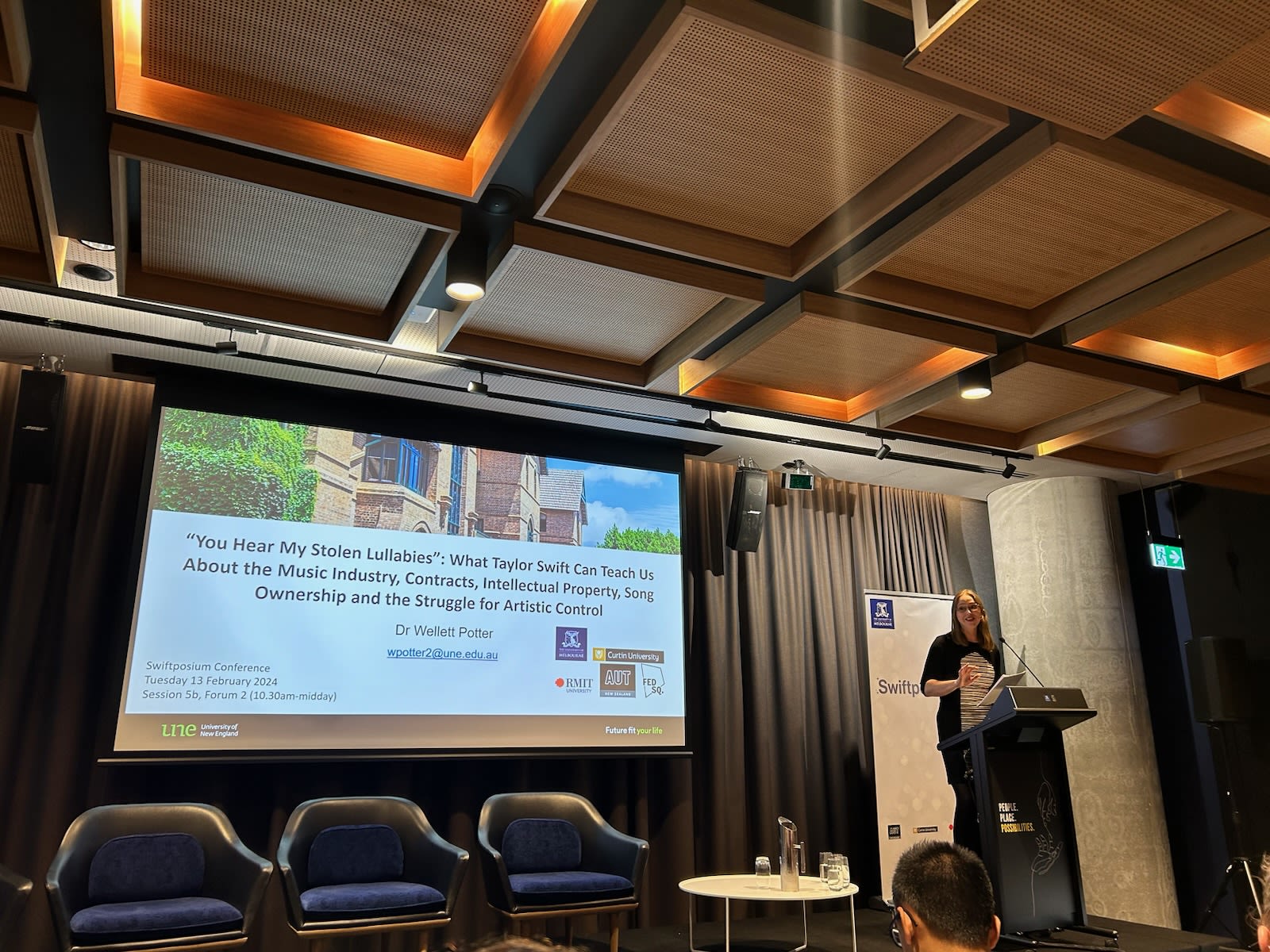 Female academic presenting her research PowerPoint from a podium.